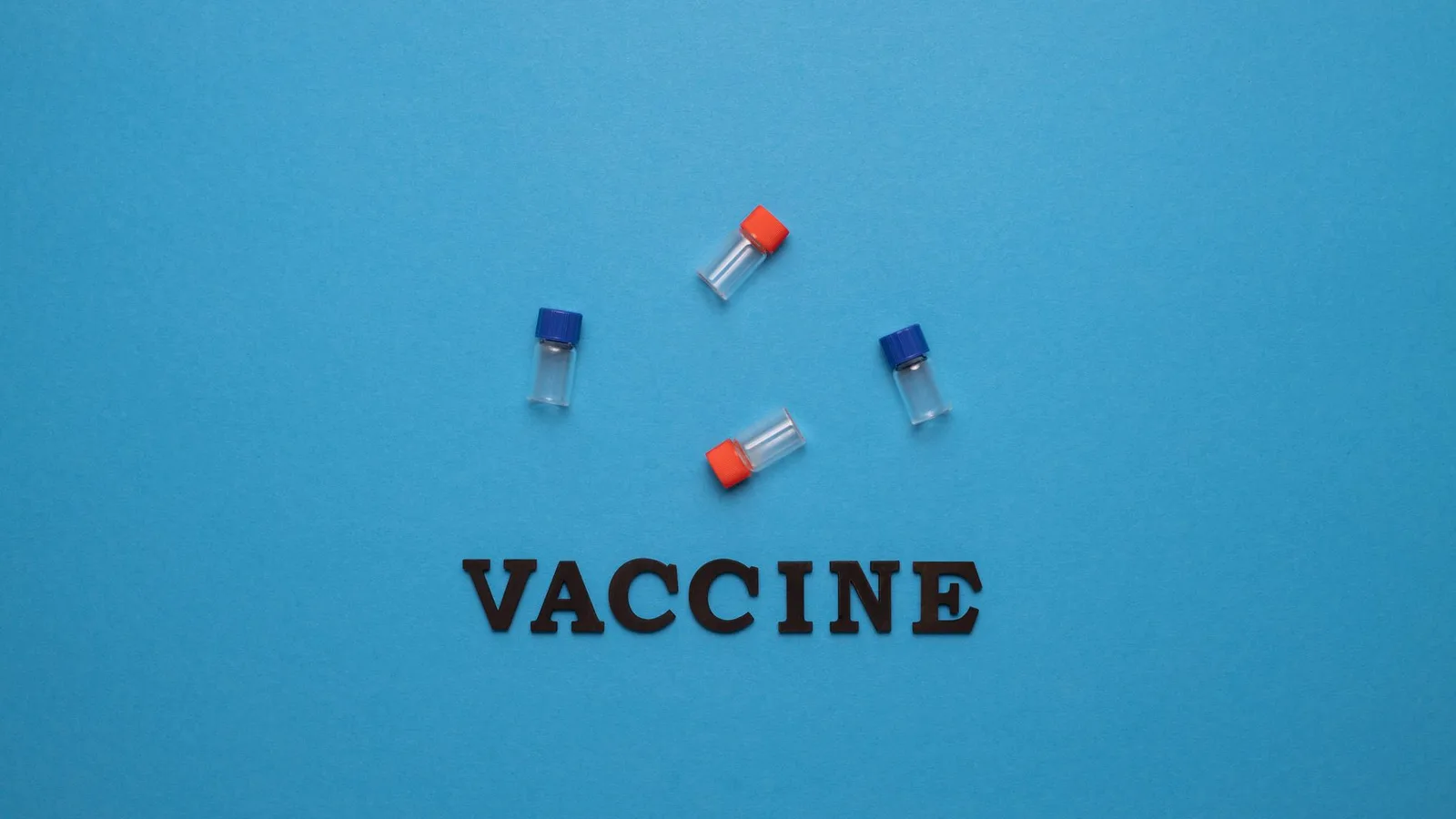 Three small vials and the word 'VACCINE' on a blue background, representing vaccination and health.
