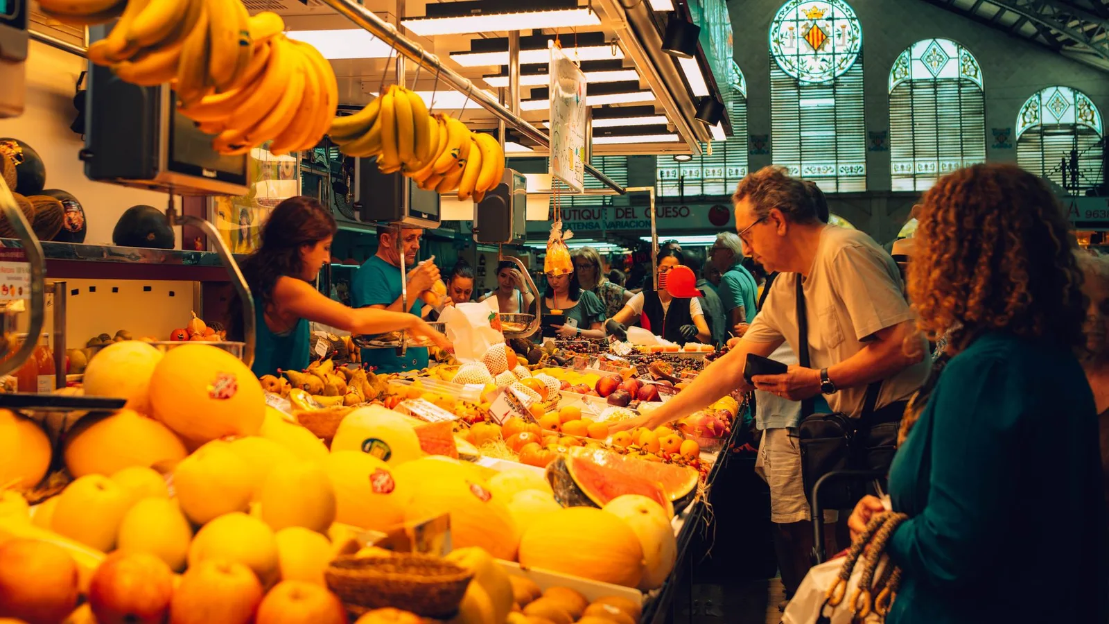 A bustling scene at Valencia's Central Market with people buying fresh fruits and produce.