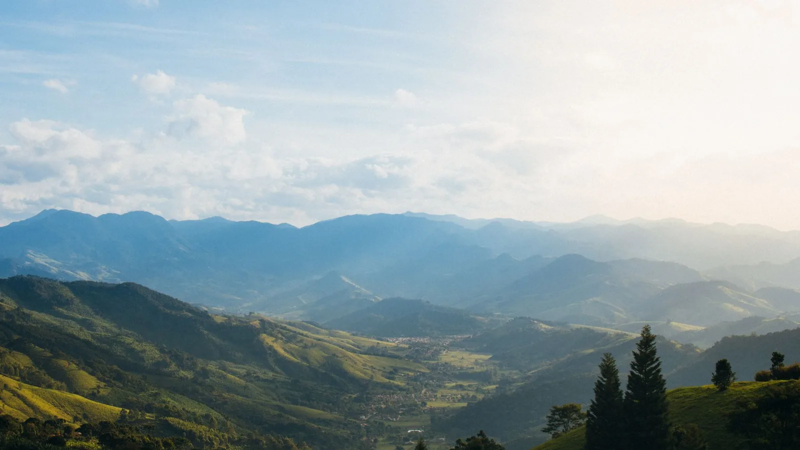 Captivating view of a sunlit valley surrounded by foggy mountains and greenery.